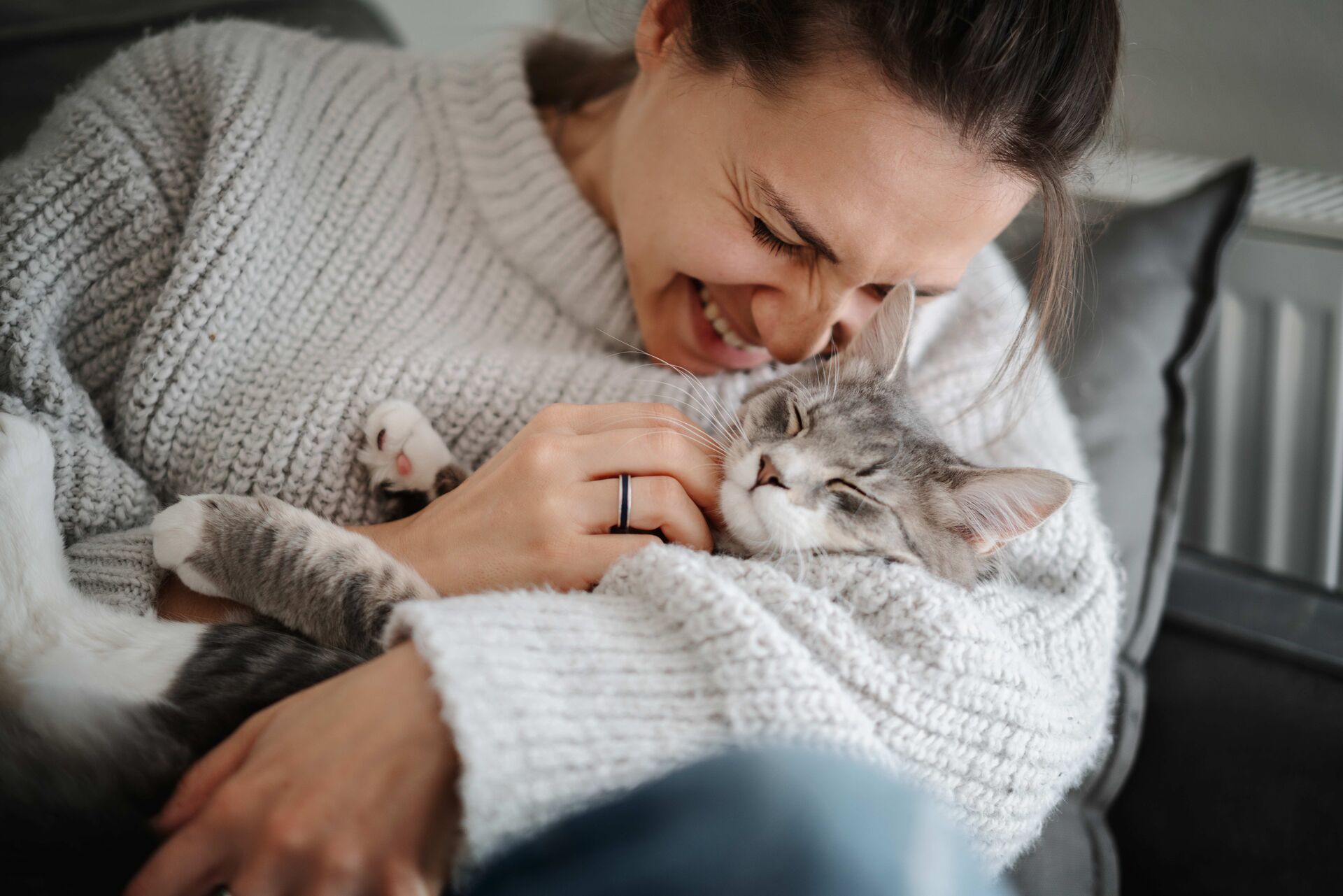 Eine Frau kuschelt mit einer Katze auf ihrem Arm.